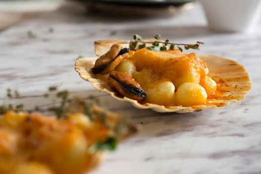 Gnocchi pasta with mussels, tomato and cream room, in vieira shell