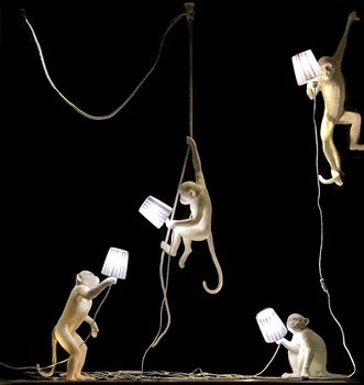FRANCE, STRASBOURG - FEBRUARY 2018 - 4 monkeys hold lighs as part of a window display in a Strasbourg restaraunt. Each white monkey figure holds a white lamp in its hand.