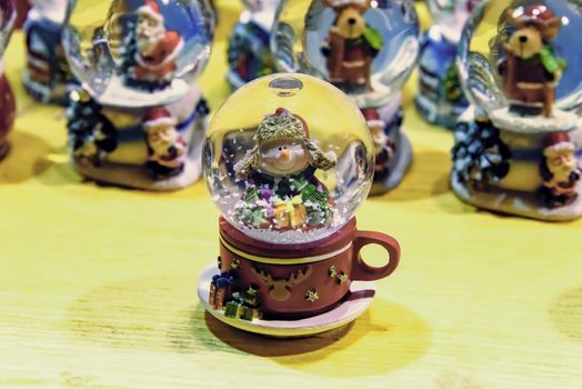 FRANCE, STRASBOURG - 20 DECEMBER 2017: Christmas snow globe, that features a snowman holding a gift, for sale at a Christmas market stall.