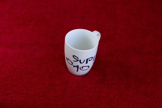 White coffe mug with writing on a red cloth