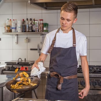 young chef prepares potatoes in a pan. Reversed by ejection.