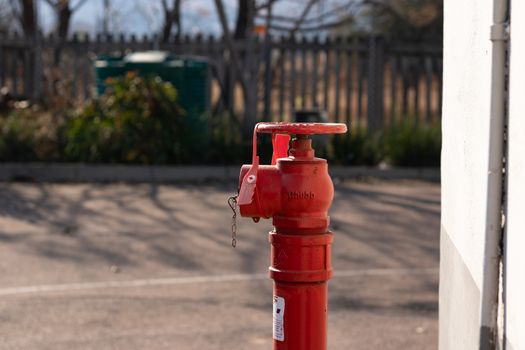 Red fire hydrant with a gren tank in the background in sunlight
