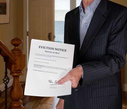 Open front door with man in suit handing an eviction notice to a defaulting renter in modern home due to missed rent