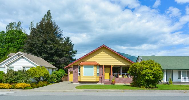 Bright yellow house with accurate lawn in front and concrete driveway to the garage