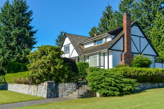 Big residential house with brick chimney and steps leading to the front yard on land terrace