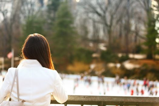 Central park skating rink - woman in New York City in late fall early winter with skating rink in background. Candid smiling multi-ethnic girl on Manhattan, USA.