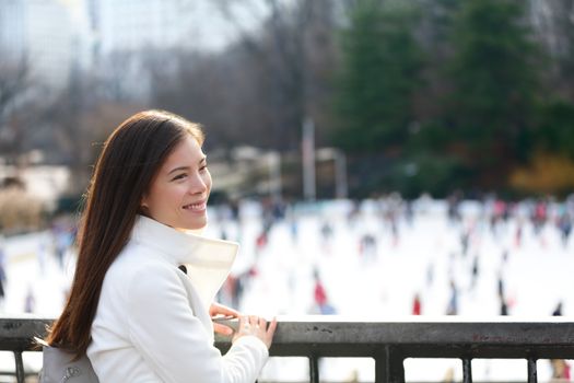 Woman in Central park, New York City in late fall early winter with skating rink in background. Candid smiling multi-ethnic girl on Manhattan, USA.