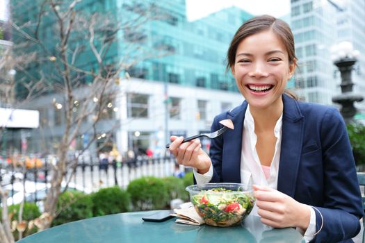 Business woman eating salad on lunch break in City Park living healthy lifestyle. Happy smiling multiracial young businesswoman, Bryant Park, Manhattan, New York City, USA