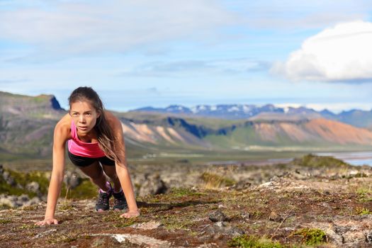 Push-ups fitness woman doing pushups or plank outside in amazing nature landscape on Iceland. Fit female sport model girl training crossfit outdoors. Mixed race Asian Caucasian athlete in her 20s.