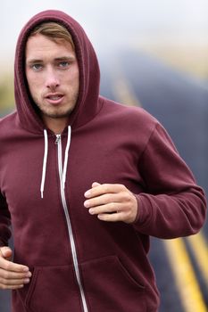 Runner athlete man running training on road in fall in sweatshirt hoodie in autumn. Male runner training outdoors jogging in nature.