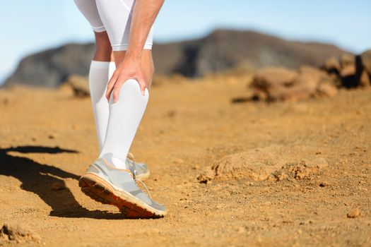 Running Cramps in leg calves or sprain calf on runner. Sports injury concept with running fitness man athlete outside.