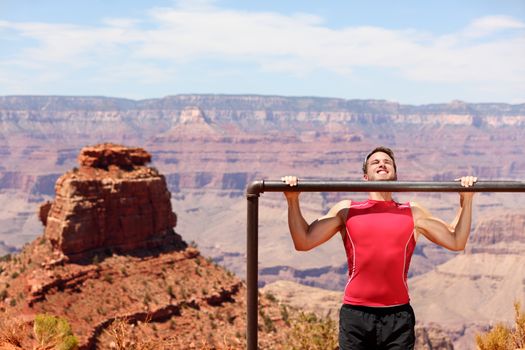 Fitness athlete man training pull ups in amazing nature landscape of Grand Canyon. Strength training fit male working out exercising outdoors in summer doing pull-ups and chin-ups.