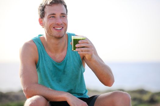 Green smoothie man drinking vegetable juice after running sport fitness training. Healthy eating lifestyle concept with young man outdoors.