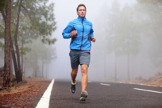 Healthy running runner man workout on mountain road. Jogging male fitness model working out training for marathon on forest road in amazing nature landscape.