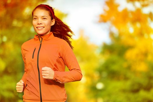 Runner woman running in fall autumn forest. Female fitness girl jogging on path in amazing fall foliage landscape nature outside.