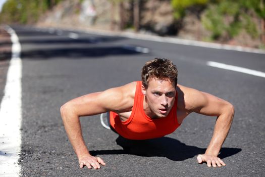 Push ups exercise man training pushup strength training outdoors. Fit muscular male fitness model warming up before running. Male runner in his 20s.