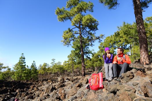 Hiking hikers couple relaxing eating lunch sandwich living healthy active lifestyle in mountain nature. Woman and man hiker sitting during hike on volcano Teide, Tenerife, Canary Islands, Spain.