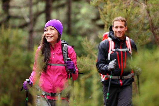 Hiking people - hikers trekking in forest on hike. Couple on adventure trek in beautiful forest nature. Multicultural Asian woman and Caucasian man living healthy active lifestyle in woods.