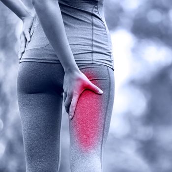 Hamstring sprain or cramps. Running sports injury with female runner. Closeup of woman back thigh.