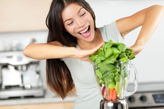 Vegetable smoothie woman making green smoothies with blender home in kitchen. Healthy raw eating lifestyle concept portrait of beautiful young woman preparing drink with spinach, carrots, celery etc.