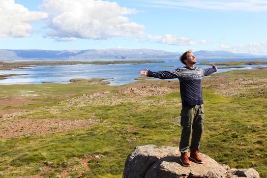 Freedom man in nature on iceland happy with arms enjoying free happiness in beautiful icelandic landscape. Male hiker relaxing in nature.