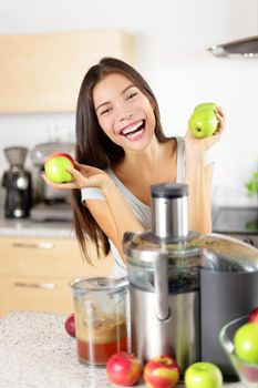 Apple juice - Woman making apple juice on juicer machine at home in kitchen. Juicing and healthy eating happy woman making green vegetable and fruit juice. Mixed race Asian Caucasian model.