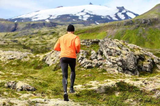 Sport athlete man - exercising trail runner running. Active male fitness model training and jogging outdoors in beautiful mountain nature landscape by Snaefellsjokull, Snaefellsnes, Iceland.