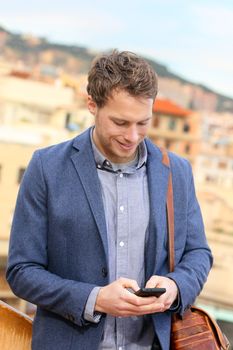 Smart phone young urban businessman on smartphone professional using smartphone using app texting sms message on smart phone wearing trendy suit jacket. Caucasian male fashion model.