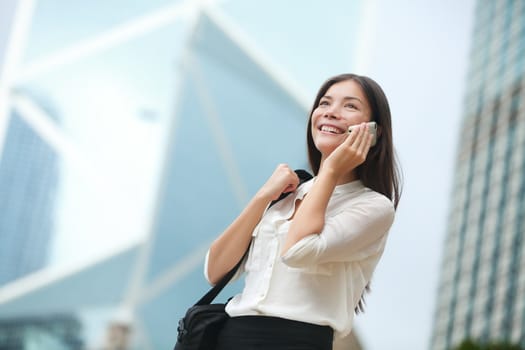 Business woman talking on smart phone in Hong Kong. Asian business people office worker talking on smartphone smiling happy. Young multiracial Chinese Asian / Caucasian female professional outside.