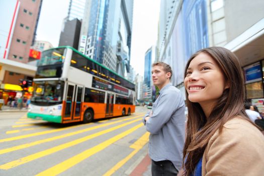 Hong Kong People walking in Causeway Bay crossing busy road with double decker bus. Urban mixed race Asian Chinese / Caucasian woman smiling happy living in city.