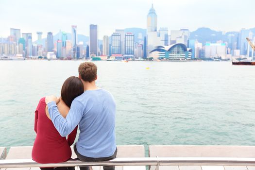 Hong Kong skyline and Victoria harbour. Couple tourists enjoying view and sightseeing on Tsim Sha Tsui Promenade and Avenue of Stars in Victoria harbour, Kowloon, Hong Kong. Tourism travel concept.