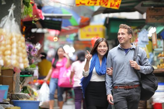 Tourists shopping in street market in Hong Kong. Couple walking looking around at small shops. Asian woman, Caucasian man.