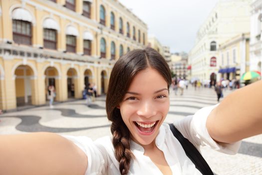 Selfie woman taking fun selfportrait in Macau, China in Senado Square or Senate Square. Asian girl tourist using smart phone camera to take photo while traveling in Macau. Travel and tourism concept.