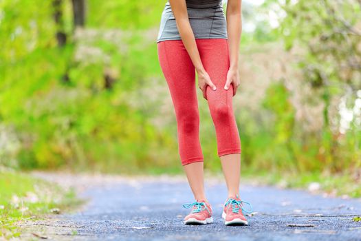 Sports muscle injury of female runner thigh. Woman running muscle strain injury in thigh. Closeup of runner touching leg in muscle pain.