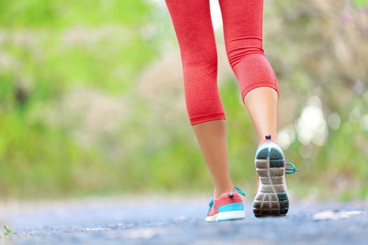 Woman with athletic legs on jog or run on trail in forest in healthy lifestyle concept with close up on running shoes. Female athlete jogging and training outdoors.