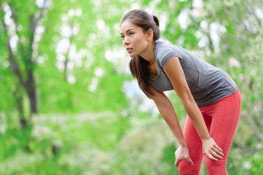 Asian woman athlete runner resting after running and jogging training outdoors in forest. Tired exhausted beautiful sports fitness model living healthy active lifestyle. Mixed race Asian Caucasian.