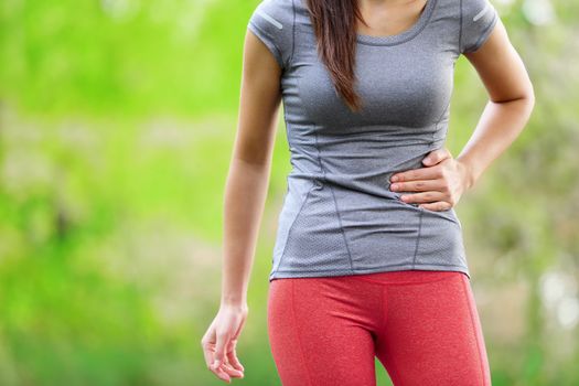 Side stitch - woman runner side cramps after running. Jogging woman with stomach side pain after jogging work out. Female athlete.