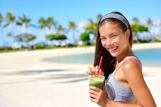 Green detox smoothie - woman drinking vegetable smoothie after fitness running workout on summer day. Fitness and healthy lifestyle concept with beautiful fit mixed race Asian Caucasian model.