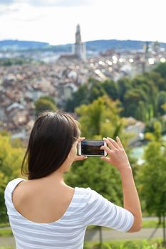 Tourist with smartphone camera in Bern, Switzerland at Rosengarten, the Rose Garden view. Woman taking photograph with smartphone at enjoying view of Berne landmarks and tourist attractions.