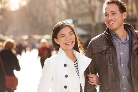 Urban modern young professionals couple walking romantic laughing talking holding hands on date. Young multicultural couple Asian and Caucasian on La Rambla Barcelona, Catalonia, Spain.