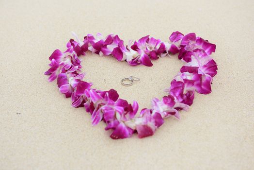 Wedding rings beach love concept. Closeup of two bands in flower heart for casual marriage celebration.