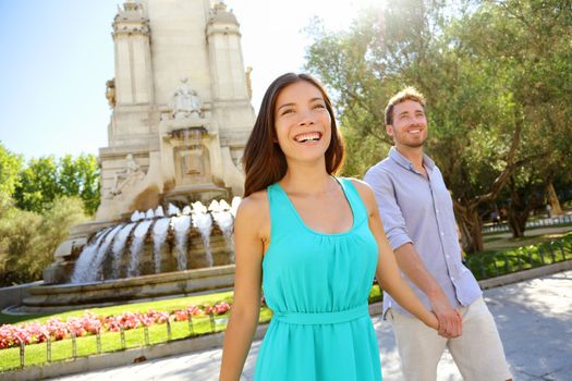 Couple walking on Plaza de Espana Madrid a popular tourist destination landmark. Romantic couple visiting Spanish tourists attractions sightseeing in Madrid, Spain. Asian woman, Caucasian man.