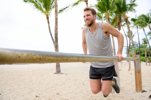 Bodyweight exercises man workout on dips bars. Male adult working out triceps and biceps on horizontal bars on beach as crossfit training routine.