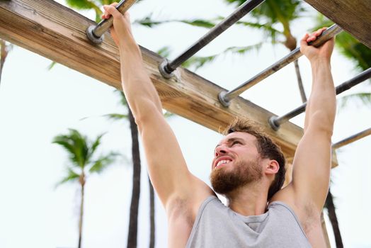 Exercise fitness athlete exercising on monkey bars. Crossfit man working out arms swinging on brachiation ladder as strength training crossfit routine.