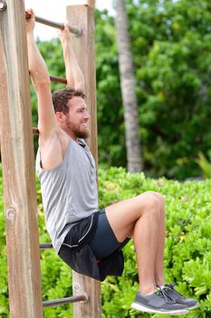 Abs exercise outside fitness station park. Man training core muscles with leg lift on vertical ladder rack on an outdoors gym center.