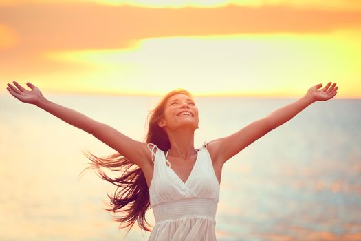 Free happy woman arms up praising freedom at beach sunset. Young adult enjoying breathing freely fresh air.