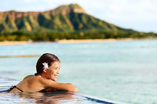 Hawaii beach travel vacation woman swimming relaxing at luxury pool hotel resort. Asian young adult on Waikiki beach, Honolulu, Oahu on exotic holidays