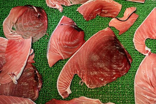 Raw tuna meat fillets or slices display in Tsukiji fish market, Tokyo, Japan. Famous touristic attraction selling raw seafood in the morning.