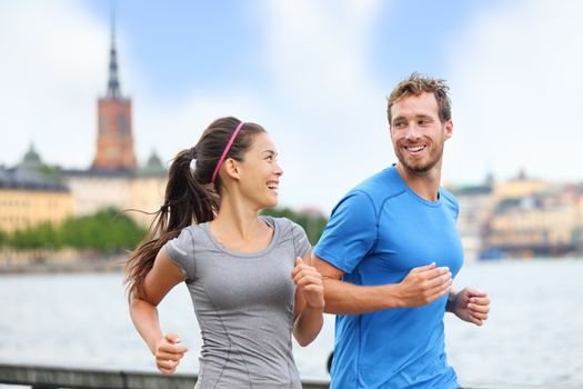 Healthy runners running in Stockholm city cityscape background. Riddarholmskyrkan church in the background, Sweden, Europe. Healthy multiracial young adults, asian woman, caucasian man.