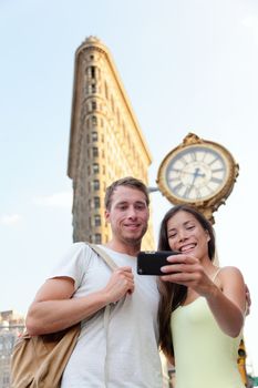 New York couple taking tourist selfie Flatiron NYC. Young adults taking a picture with smartphone in front of attraction building in NYC in summer.